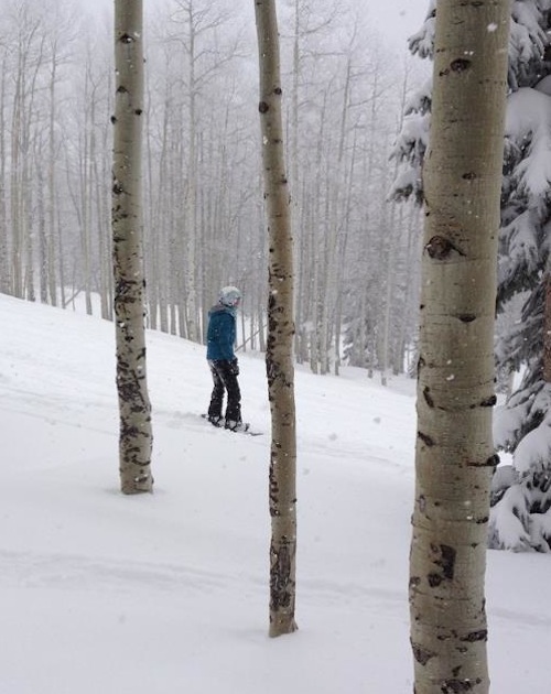 Lindsay snowboarding through the woods