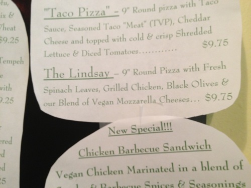 Menu giving description of the Lindsay Pizza with spinach, black olives, vegan chicken, and vegan cheese