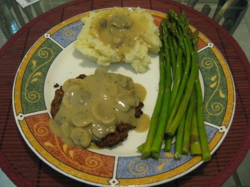 mushroom gravy over mushroom burger and mashed potatoes with a side of asparagus